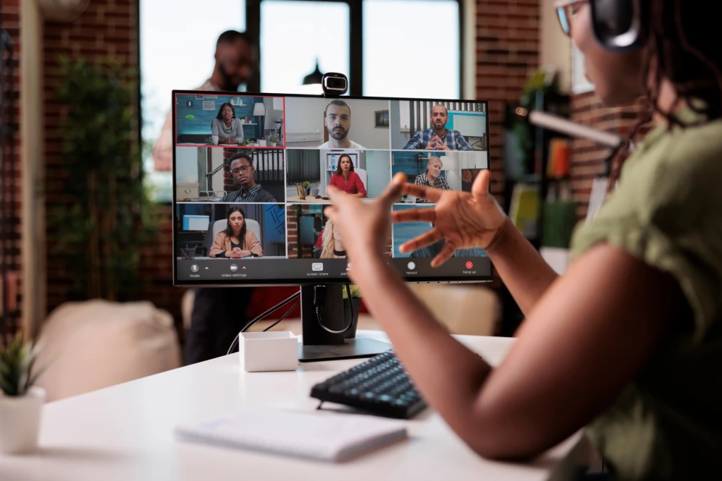 A lady engaged in a Zoom call on a computer screen featuring multiple participants