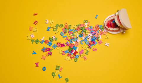 A mouth with multi coloured letters coming out of it