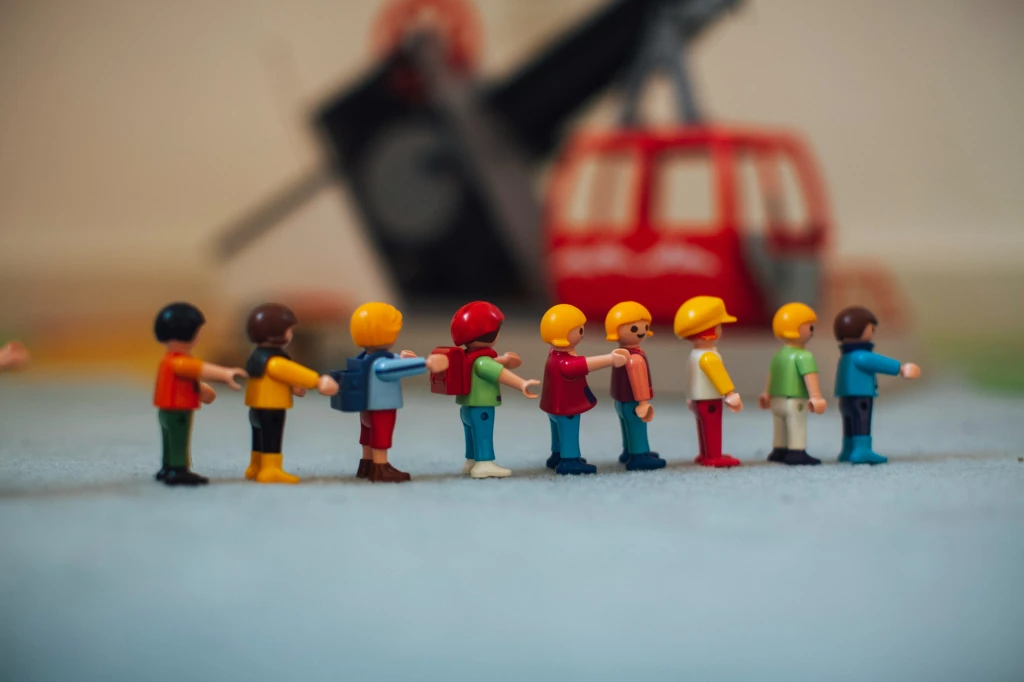 Lego figures standing in a line with some who have their hand on the shoulder of the person in front