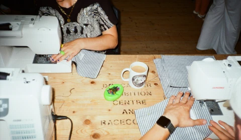 Photograph of people sewing, using sewing machines