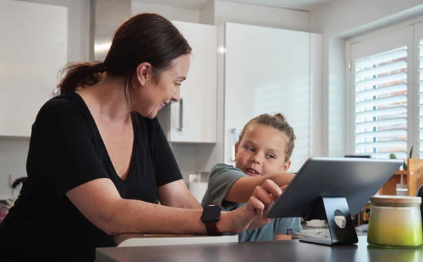 A woman and child interacting with a tablet computer